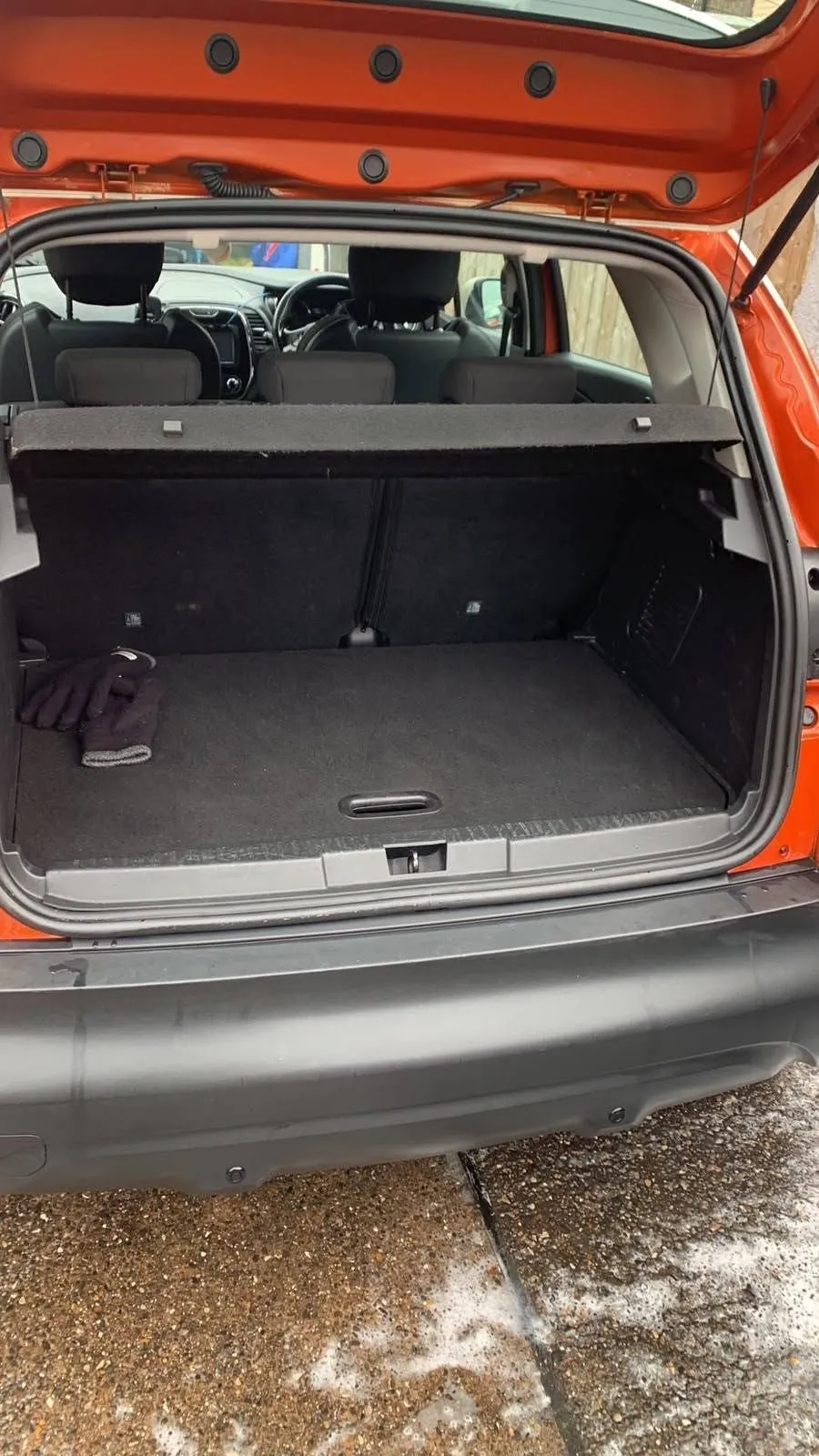 Open boot of an orange Renault Captur, vacuumed carpet