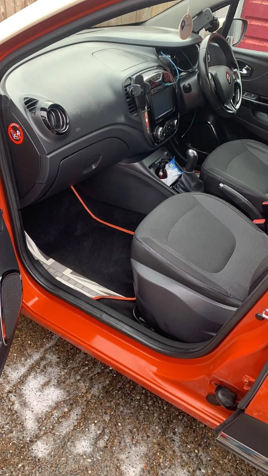 Front cabin of an orange Renault Captur with orange trim, seats and dashboard cleaned
