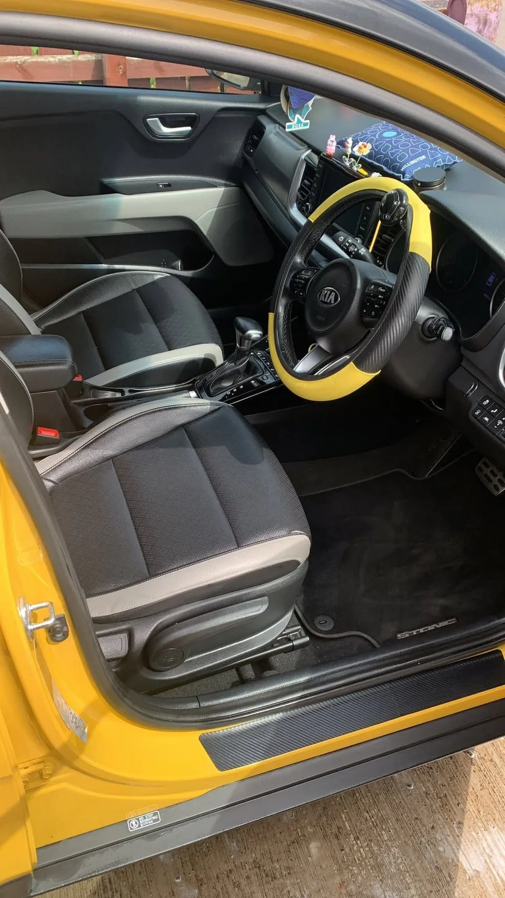 Cabin of a Kia with yellow and black trim, seats and mats cleaned, yellow steering wheel cover