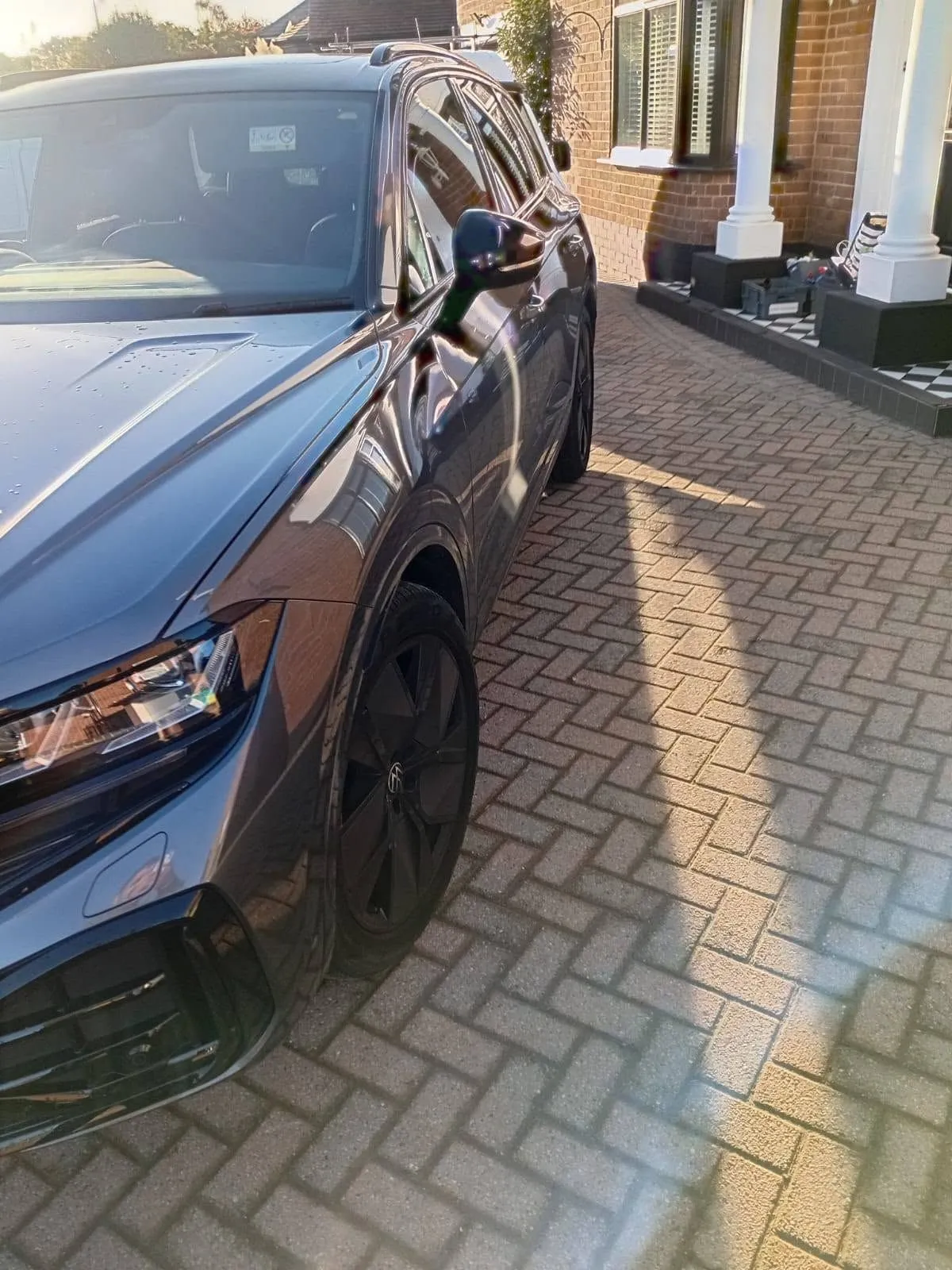 Grey Volkswagen Touareg on a herringbone driveway in the sun, paintwork washed and dried